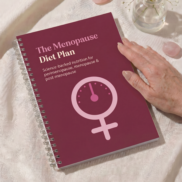 Book titled 'The Menopause Diet Plan' on a white surface with a hand touching it.